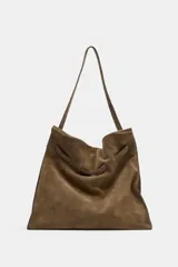 Maxi bolso de hombro confeccionado en serraje, con diseño de silueta holgada y detalle de tira entrelazada en la parte frontal. Cuenta con asa de hombro, cierre mediante botón imantado y bolsillo interior con cremallera.