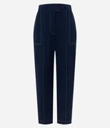 Pantalón de vestir negro, estilo carrot (holgado en cadera y ajustado en tobillo), de cintura alta con trabillas y cierre tradicional. Presenta recortes verticales con costura aparente en el frente.