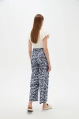 Pantalón de algodón estampado con diseño botánico de hojas en tonos verdes sobre base blanca, de corte holgado, tiro medio y cintura elástica con cordón de ajuste ajustable.