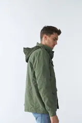 Campera de gabardina verde militar con capucha desmontable y ajustable, cierre frontal con cremallera y múltiples bolsillos con solapa.
