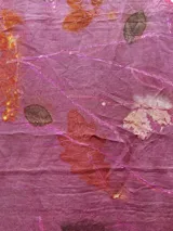 Mantel rectangular de lino color rosa con estampado de hojas y flores en tonos naranja, marrón y blanco.