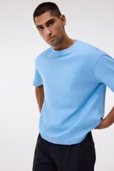 Remera de algodón celeste de corte relajado, con cuello redondo ribeteado y mangas cortas con hombros caídos.
