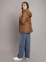 Campera puffer corta Calvin Klein de color marrón, con diseño capitonado de líneas horizontales, cuello alto, cierre frontal de cremallera y bolsillos laterales con cierre.