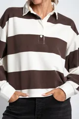 Sweater de estilo polo con diseño de rayas horizontales anchas en color marrón y blanco. Presenta cuello camisero, cierre frontal con botones y mangas largas con puños ajustados.