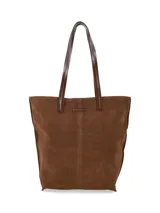 Cartera tipo tote bag de gamuza color marrón, con asas largas de cuero liso y costuras visibles en el centro.