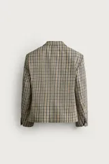 Blazer de corte boxy fit de Zara, confeccionado en tejido con algodón con estampado a cuadros en tonos beige, negro y blanco. Cuenta con cuello de solapas de muesca, manga larga con botones en los puños, bolsillos de vivo en el pecho y de plastrón en la cadera, y cierre frontal con un botón.