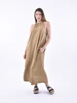 Vestido largo tostado de corte holgado, con cuello halter fruncido, sin mangas y bolsillos laterales.