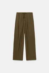 Pantalón fluido de tiro alto color verde militar, con cintura elástica ajustable con cordones y detalles de cuentas de madera. Tiene bolsillos delanteros y pierna recta.