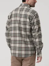 Camisa de manga larga RKF modelo Flannel, confeccionada en algodón orgánico. Presenta un diseño de cuadros en tonos beige, verde, marrón y naranja, con cierre frontal de botones, cuello camisero y un bolsillo aplicado en el pecho con detalle bordado.