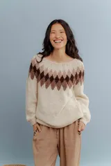 Buzo tejido a mano en lana merino, con diseño de patrón geométrico en forma de rombos en la parte superior en tonos marrones sobre base color crema.
