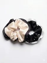 Kit de accesorios para el cabello que incluye un neceser transparente con borde blanco, dos scrunchies (uno negro con perlas y uno beige), dos clips livianos, una pinza dorada, un peine protector para desenredar y un peine para abrir ondas y rulos.