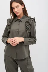 Camisa de manga larga color verde militar, con cuello clásico, cierre frontal de botones y detalle de volados en los hombros.