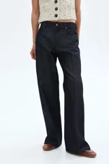 Jean de cinco bolsillos en denim de algodón color azul oscuro, de tiro medio y pierna recta muy ancha. Presenta pliegues cosidos marcados en el frente de cada pierna.