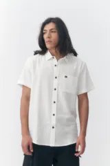 Camisa de manga corta Quiksilver modelo Robin Lisa, color blanco, de corte regular con cierre frontal de botones, cuello camisero y un bolsillo aplicado en el pecho con pequeña etiqueta de la marca.