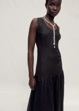 Vestido largo de corte evasé, sin mangas y con cuello redondo. Confeccionado en una mezcla de lino y ramio, presenta un diseño minimalista con falda de vuelo y cierre posterior.