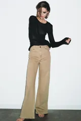 Jeans de tiro alto con corte wide leg y largo completo. Presenta diseño de cinco bolsillos, cintura con trabillas y cierre frontal con cremallera y botón.