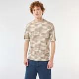 Remera de algodón con cuello redondo y estampado de camuflaje en tonos verde militar, beige y marrón, de corte relajado y mangas cortas.