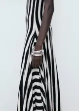Vestido largo de punto fino con diseño evasé, cuello caja y tirantes anchos. Presenta un estampado de rayas verticales en blanco y negro y un bajo asimétrico.