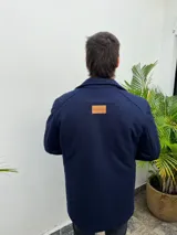 Tapado de paño de corte recto y largo medio en color azul marino, con cuello alto, cierre frontal con botones y bolsillos funcionales.