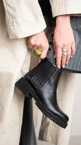 Bota tipo chelsea de cuero con acabado desgastado, paneles laterales elásticos y suela track robusta.