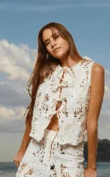 Chaleco de algodón color crema con calados y bordados florales, con lazos en el frente.