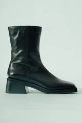 Bota de caña media confeccionada en cuero negro, con diseño minimalista, punta cuadrada y taco ancho geométrico.