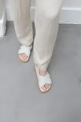 Sandalias planas color celeste y blanco, con tiras anchas cruzadas y suela color caramelo.