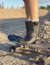 Bota estilo tejana de cuero vacuno color bordó, con detalle de argolla metálica y remaches decorativos.