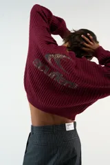 Sweater tejido burdeos de textura acanalada, de corte relajado con cuello redondo, hombros caídos y mangas largas. Cuenta con un gráfico bordado del logo Scuffers en la espalda con estampado de leopardo y terminaciones acanaladas en puños y cintura.
