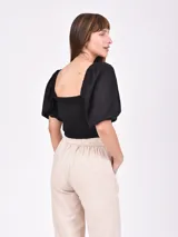 Blusa corta negra con escote cuadrado, mangas abullonadas 3/4 y cierre frontal con botones.