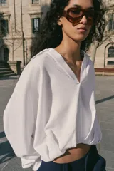 Camisa verde militar confeccionada en mezcla de lino, con cuello solapa, escote en pico, manga larga y diseño asimétrico con pliegues en la parte delantera.