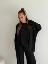 Buzo de tejido de punto acanalado color negro, con cuello redondo, mangas largas y corte holgado.