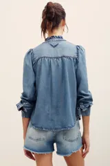 Camisa de denim de lyocell con cierre frontal de broches metálicos, cuello redondo con volados fruncidos y mangas largas con puños doblados.