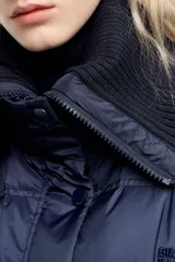 Chaqueta acolchada de corte globo en tejido técnico color azul marino, con cierre frontal de cremallera y botones a presión, maxicuello de punto acanalado, manga larga con puño elástico y bajo de punto.