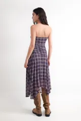 Vestido midi de palabra de honor con estampado de cuadros en tonos morados y beige. Presenta fruncidos en los laterales y un bajo asimétrico.