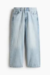 Jean de cinco bolsillos en denim de algodón rígido, de corte holgado con pierna amplia y tiro caído, en color celeste claro con efecto desteñido.