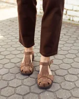 Sandalias de cuero gamuzado color marrón, tipo romanas, con tiras entrelazadas, talón cerrado y tira ajustable con hebilla metálica en el tobillo.
