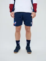 Bermuda deportiva Umbro del Club Nacional de Football, color azul marino, con cordón ajustable en la cintura, bolsillos laterales, el escudo del club en una pierna y el logo de la marca en la otra.