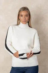 Buzo de punto acanalado color beige, con cuello alto, corte oversize y mangas largas. Presenta costuras decorativas en color negro que recorren los hombros y las mangas.