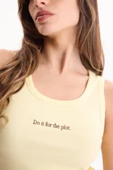 Musculosa de rib de algodón color amarillo claro, de calce ajustado con cuello redondo y diseño sin mangas. Cuenta con un delicado bordado frontal con la frase "Do it for the plot.".