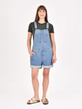 Monoprenda tipo jardinera de jean en color azul claro, con diseño de short, bolsillos laterales y bolsillo frontal en el pecho.