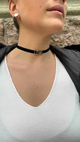 Gargantilla tipo choker de terciopelo negro con dije metálico dorado con la palabra "LOVE".
