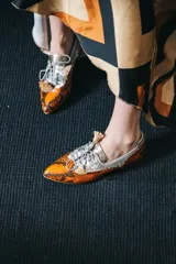 Zapato blucher de cuero con estampado animal print en tonos naranja y plateado, con cordones y detalle de borlas.