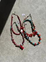 Collar hecho a mano con cuentas de coral rojo y nácar blanco, engarzadas en cadena metálica plateada.