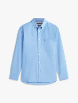 Camisa de corte regular confeccionada en algodón Oxford elástico y ligero, color celeste. Cuenta con cuello abotonado, mangas largas con puños redondeados, bolsillo de parche en el pecho con el logo bordado y bajo redondeado.