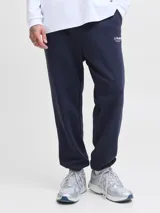 Pantalón de jogging color azul marino, con corte regular y tejido de punto con interior afelpado. Presenta cintura elástica con cordón ajustable y puños acanalados en los tobillos. Incluye un pequeño logo estampado en blanco en la parte superior de la pierna.