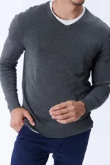 Buzo de punto gris melange con escote en V, de manga larga y puños acanalados.
