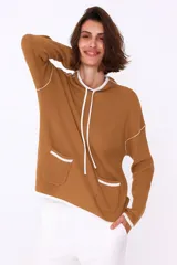 Sweater color crema con cuello alto, corte holgado y detalles en negro en cuello, puños, ruedo y bolsillos frontales.