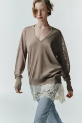 Jersey de punto con escote en pico y manga larga, diseñado con una doble capa que incorpora un bajo de encaje en color crudo.