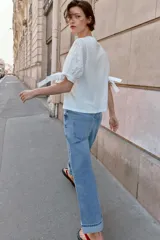 Camiseta de cuello redondo confeccionada en algodón, con mangas cortas abullonadas de tejido bordado perforado y detalle de lazadas en los puños.